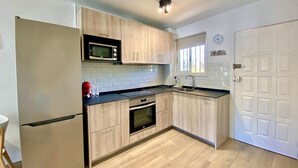 Une cuisine moderne avec des meubles de couleur bois clair, un four à micro-ondes en acier inoxydable, un four encastré et un évier.