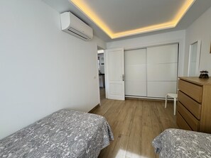 Een slaapkamer met twee bedden, een kledingkast, een dressoir en een airconditioning.