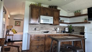 A modern kitchen with wooden cabinets, a built-in microwave, and a large island with stools. - Cozy Lakeview Cabin, Boat Parking, Breathtaking Lake View, One Hour from Tulsa  (Afton)