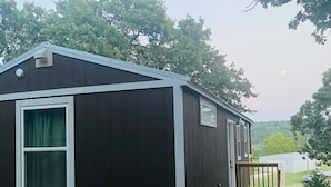 A single-story, dark-colored cabin with a small porch and a wooden deck. - Cozy Lakeview Cabin, Boat Parking, Breathtaking Lake View, One Hour from Tulsa  (Afton)