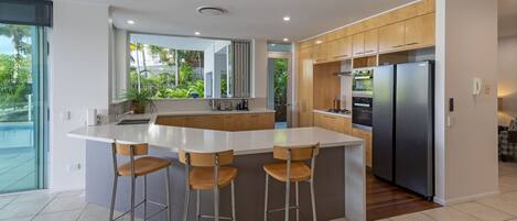 A modern kitchen with a large island, bar stools, and a built-in oven.