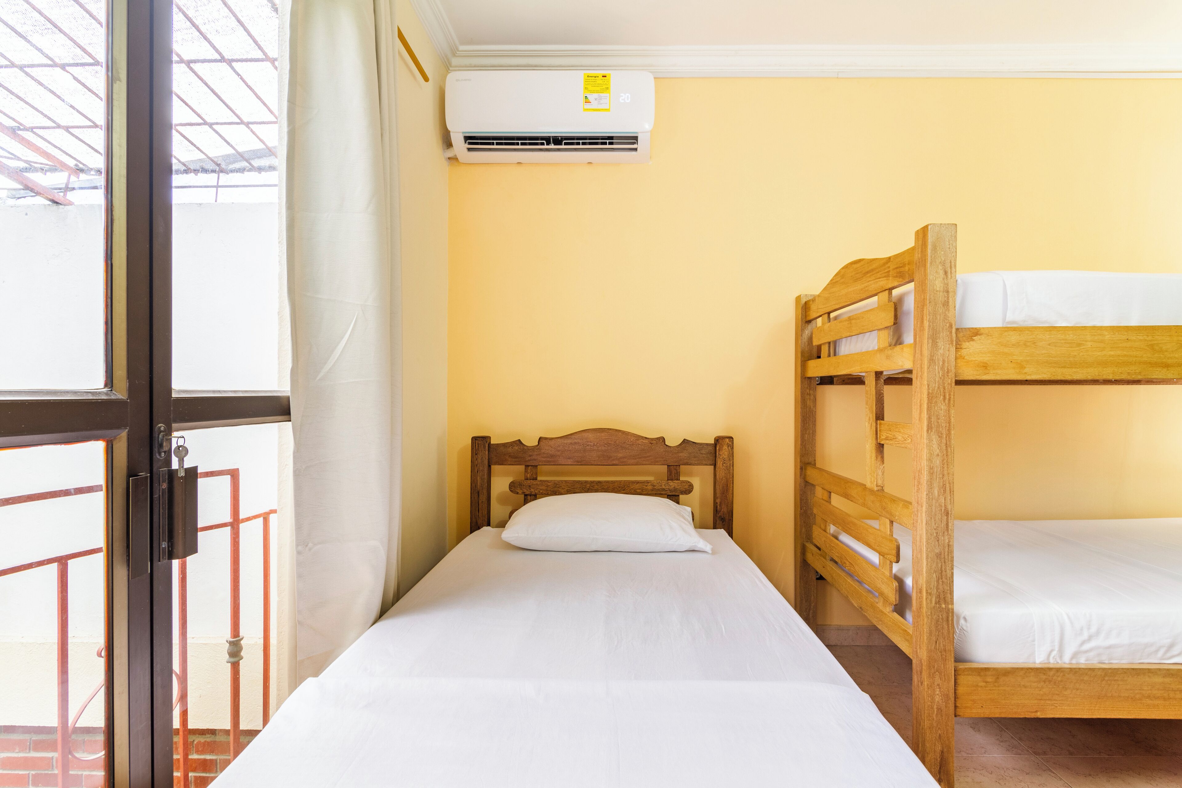 Un letto singolo con una testiera in legno e biancheria da letto bianca in una stanza con pareti gialle.