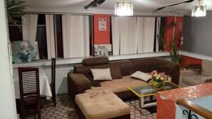 A living room with a sofa, ottoman, and a glass coffee table. - The Imperial Hostal (Quito)