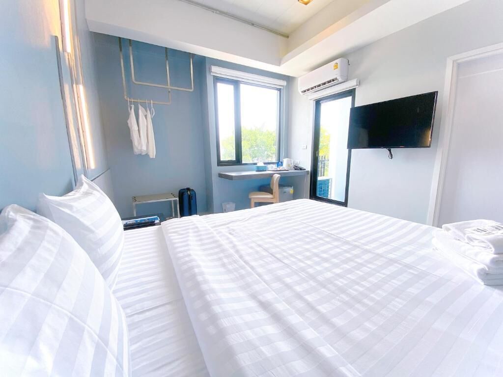 Une chambre d’hôtel dotée d’un grand lit, d’un bureau avec une chaise, d’un téléviseur fixé au mur et d’une fenêtre donnant sur l’extérieur.