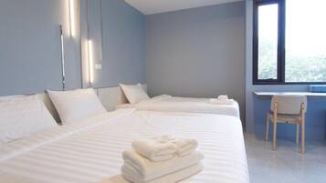 A hotel room with two beds, a desk, and a chair.
