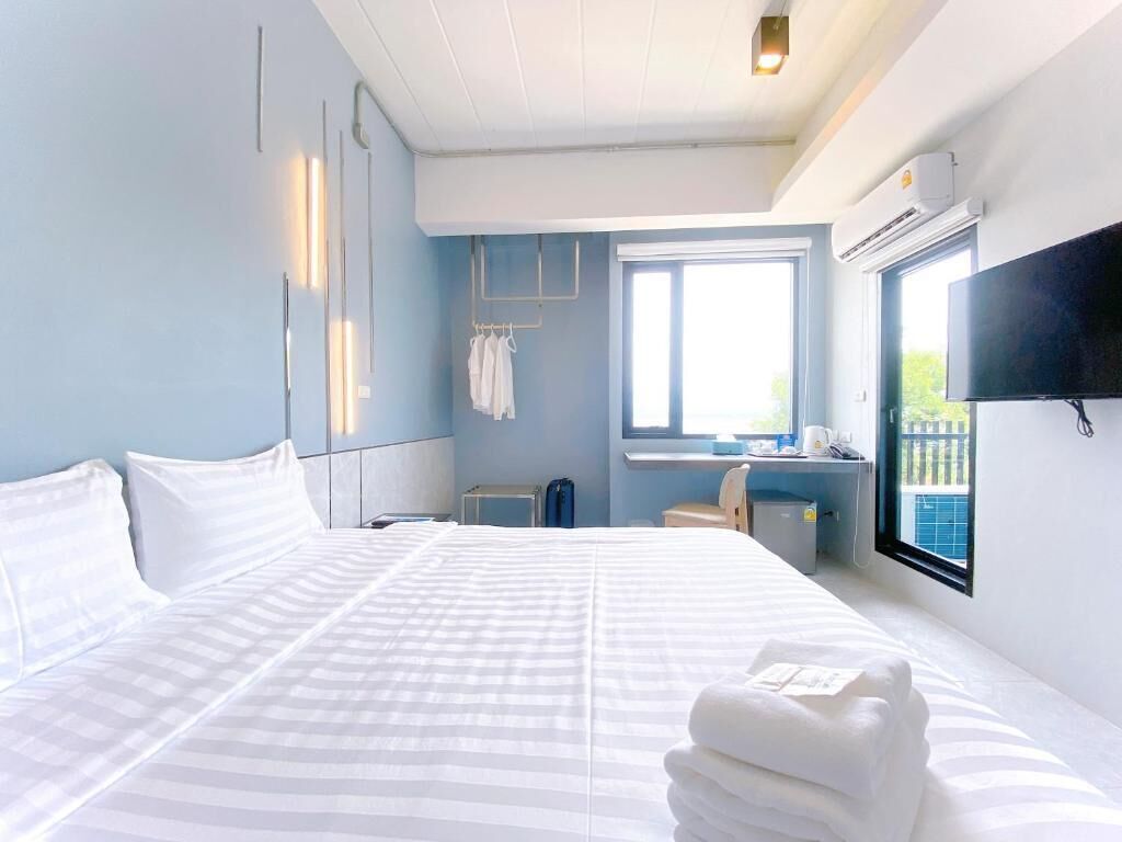 Una habitación de hotel con una cama grande, un escritorio, una silla, un televisor y una ventana.
