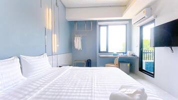 Una habitación de hotel con una cama grande, un escritorio, una silla, un televisor y una ventana.