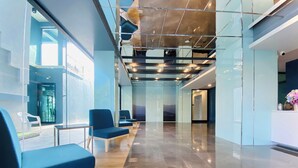 A modern lobby with a glass wall, blue seating, and a polished floor. - ABIZZ Hotel KwanPhayao (Phayao)