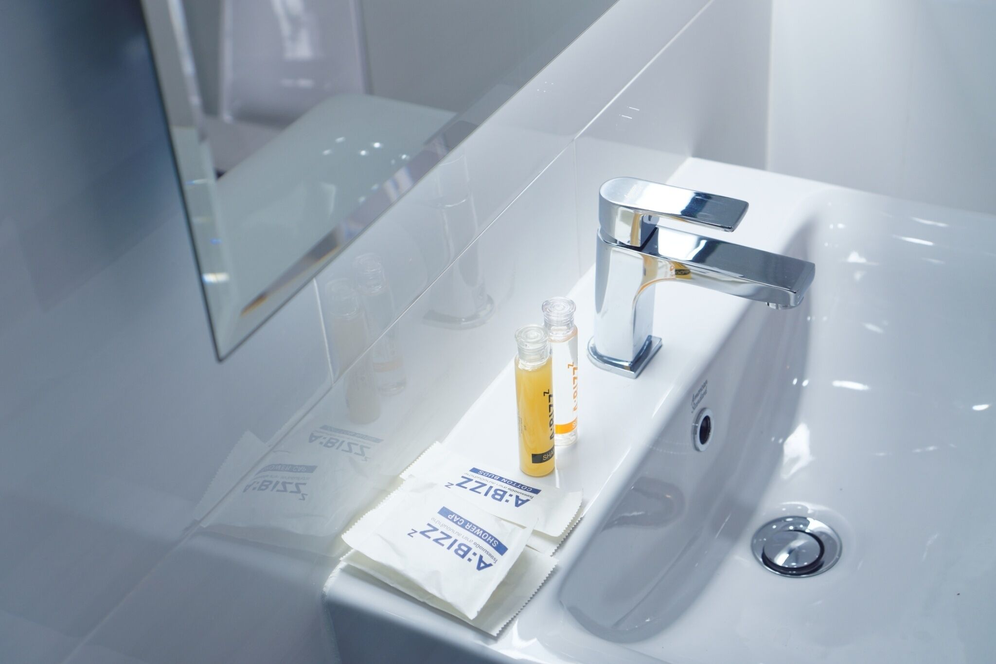 Un baño moderno con un lavabo blanco, grifo cromado y dos botellas de jabón de manos.