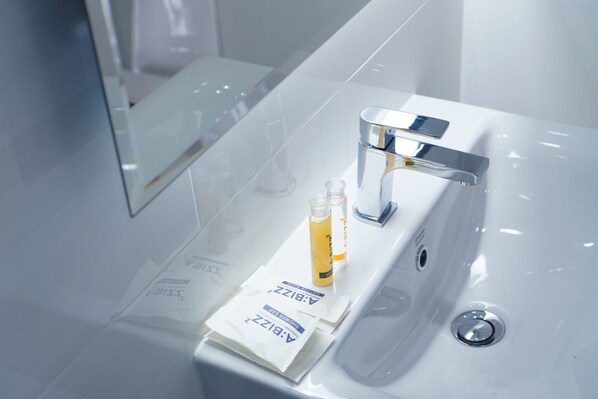 Un baño moderno con un lavabo blanco, grifo cromado y dos botellas de jabón de manos.