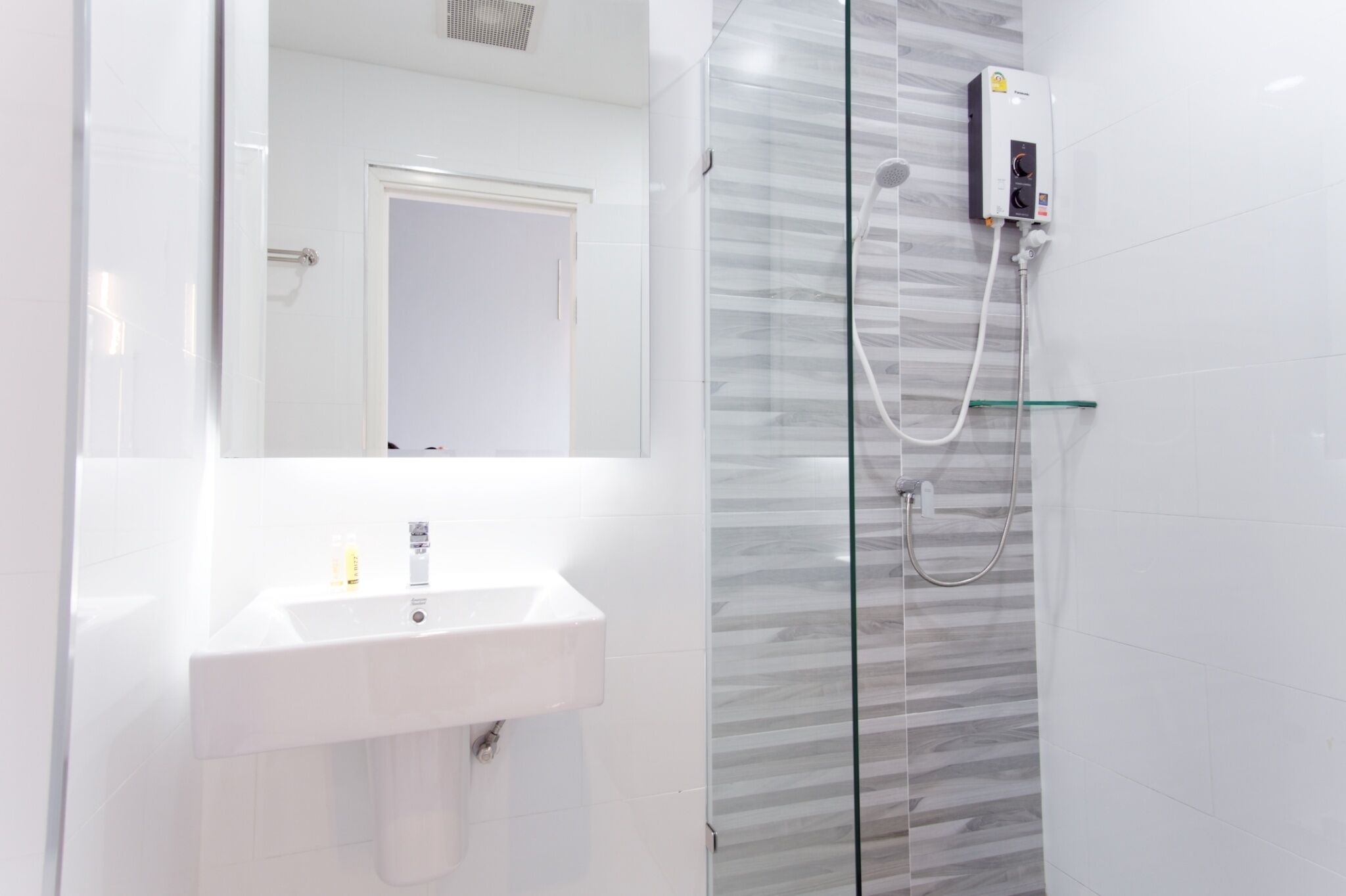 Une salle de bain moderne avec une douche à parois de verre, un lavabo blanc et un miroir.