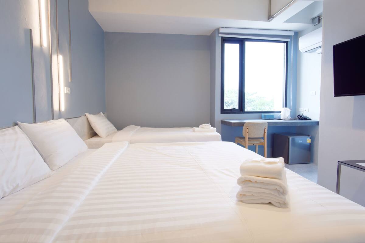 Une chambre d’hôtel avec deux lits, un bureau, une chaise et un téléviseur.