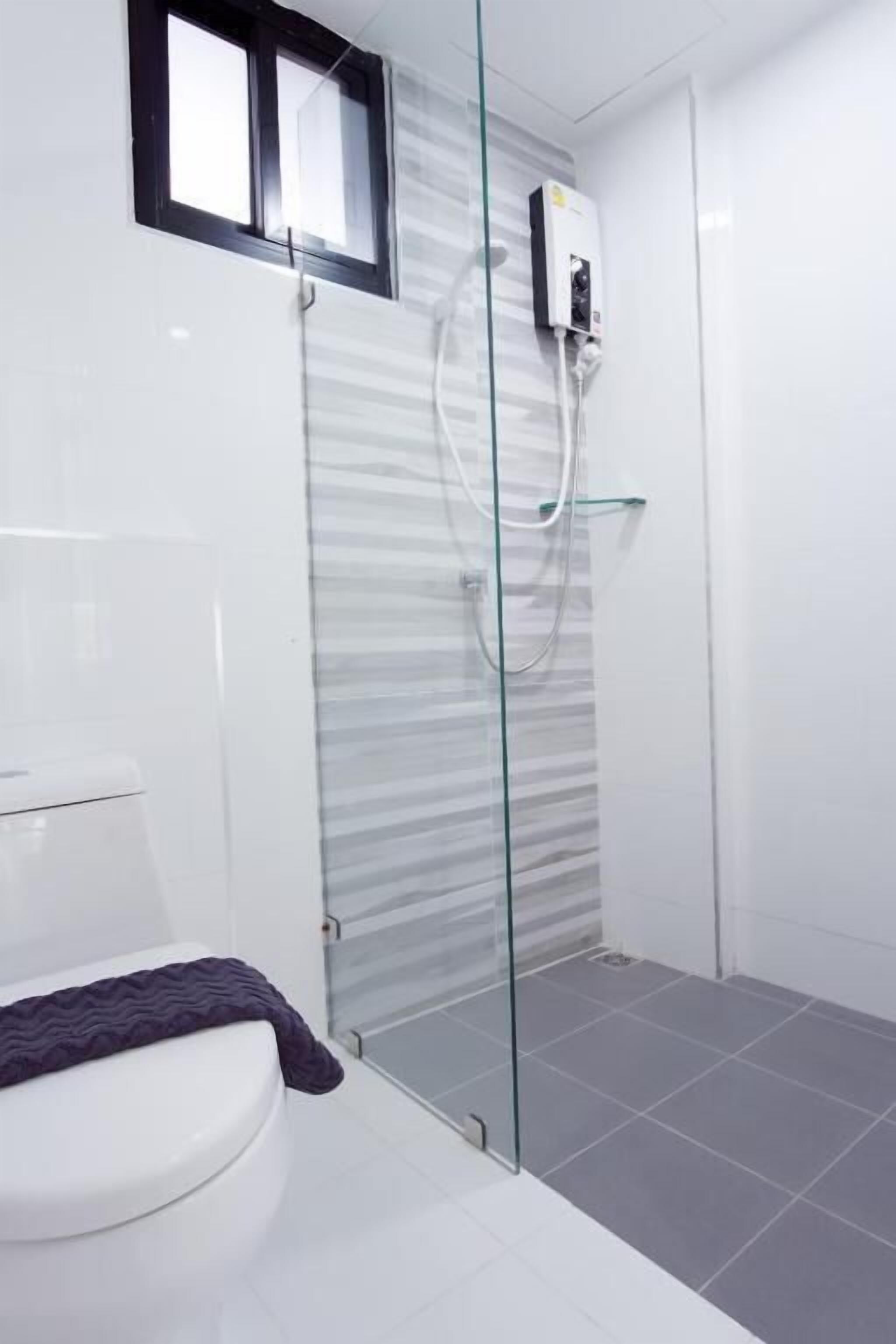 Un bagno moderno con doccia vetrata, un water e un piccolo oblò.