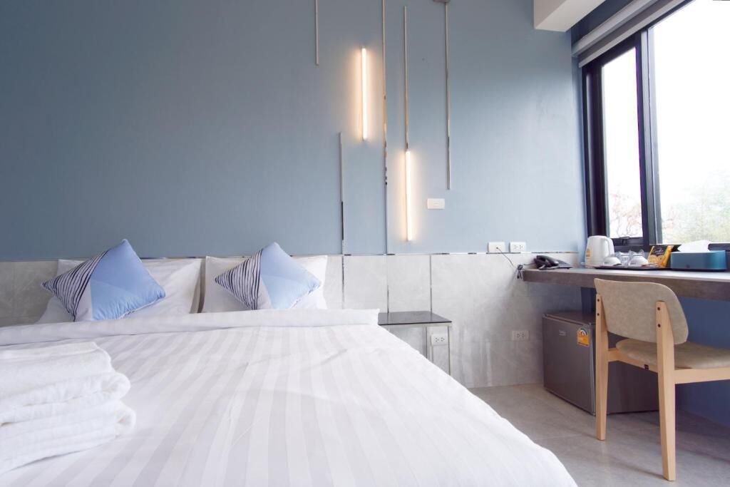 A modern hotel room with a bed, a desk, and a chair.