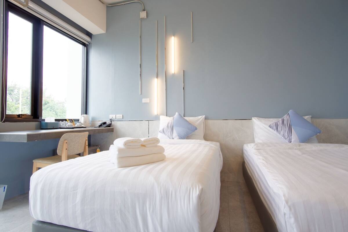 Une chambre d’hôtel moderne avec deux lits, un bureau et une chaise.