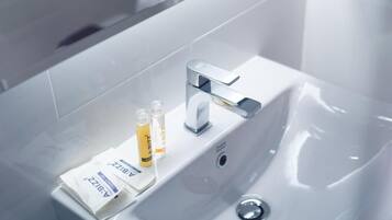 A bathroom sink with a modern faucet and two bottles of hand soap.