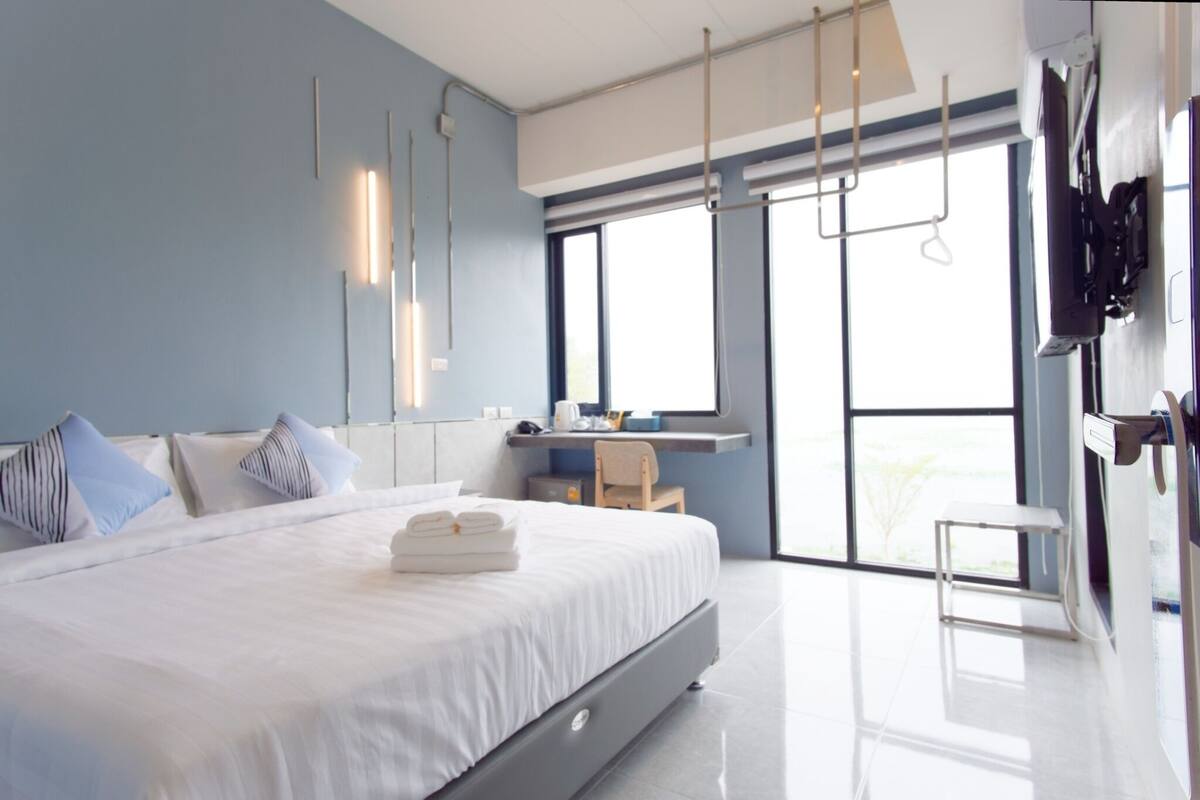 Une chambre d’hôtel moderne avec un grand lit, un bureau et un téléviseur fixé au mur.