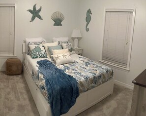 A bedroom with a bed, a nightstand, a lamp, and decorative wall art.