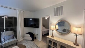 En moderne stue med et fladskærms-tv, en sofa, et sofabord og et konsolbord med lamper.