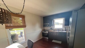 A compact kitchen with dark cabinets, a stainless steel refrigerator, a microwave, and a window providing natural light. - Newly Updated Home w/Easy Access to I-85/I-40  (Haw River)