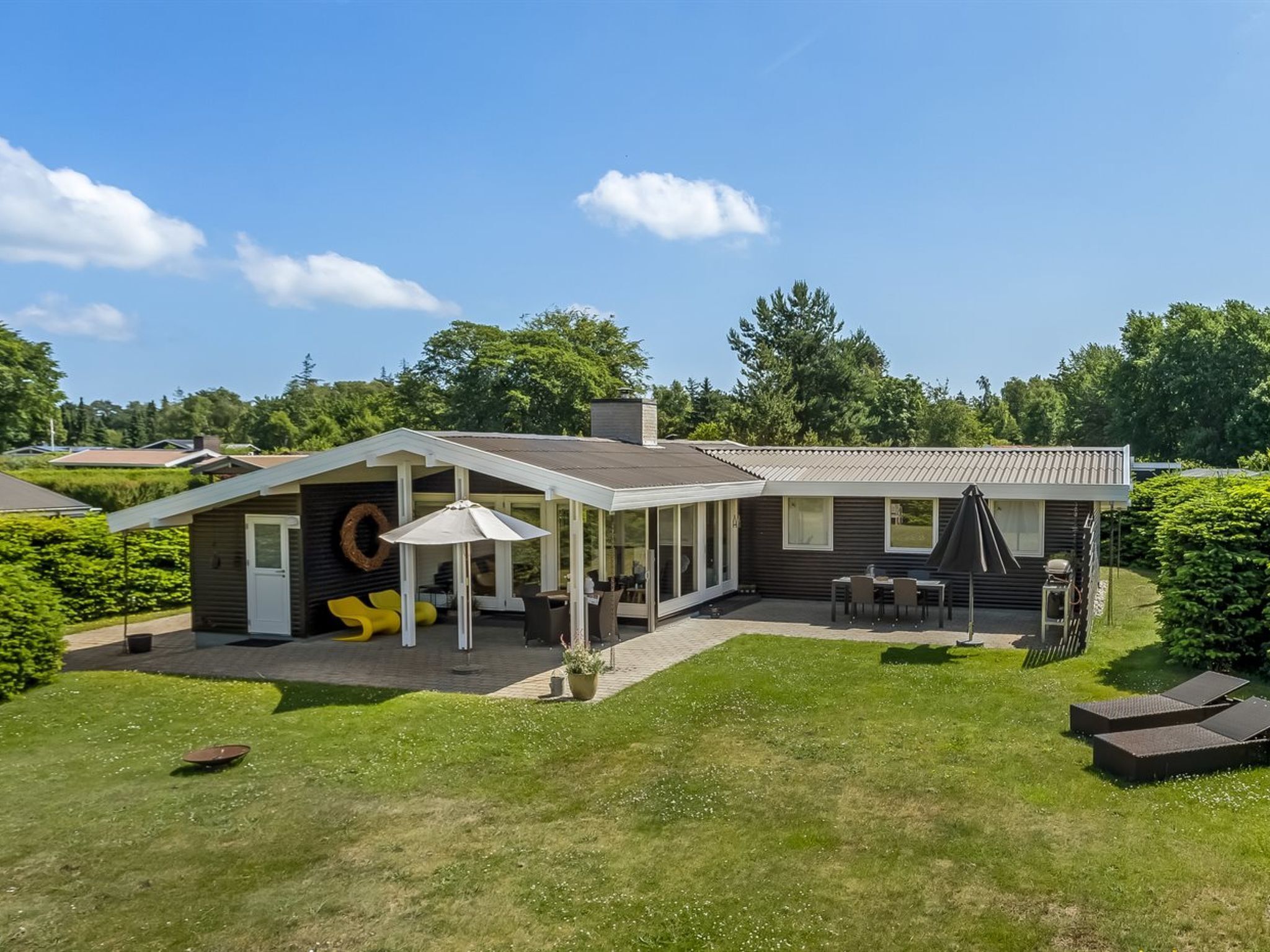 A modern house with a covered patio, outdoor seating, and a well-maintained lawn.