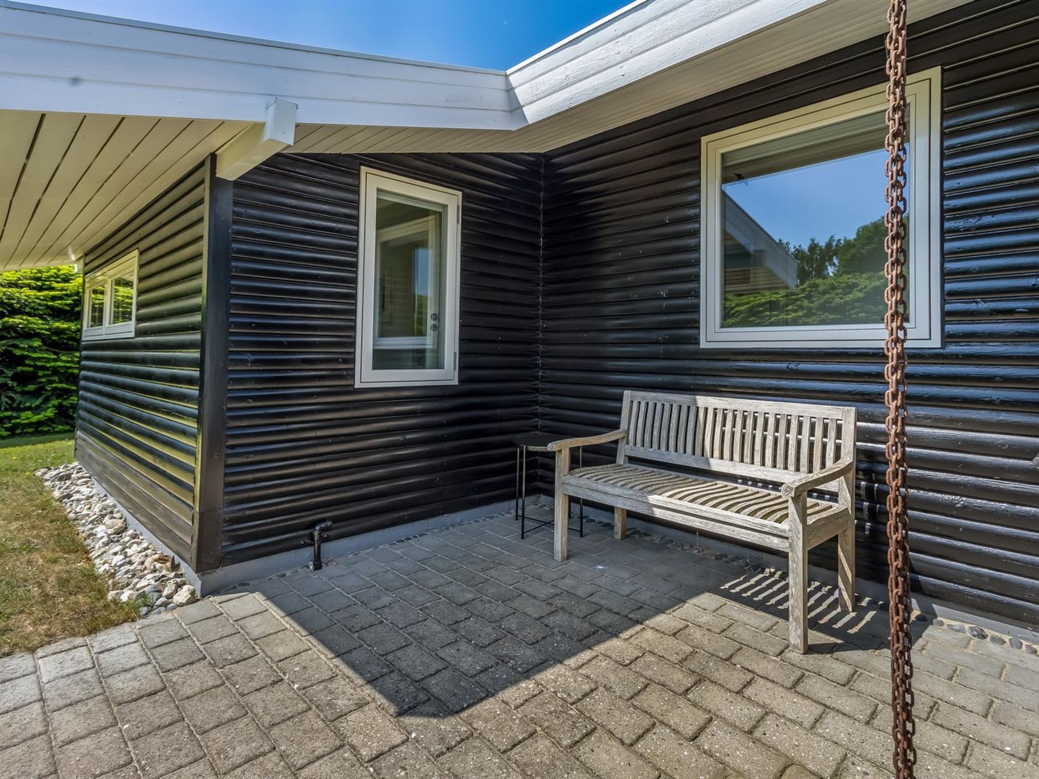 Une cabane en bois avec un banc et deux fenêtres.