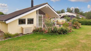 A single-story house with a sloped roof, a chimney, and a covered porch with a table and chairs. - "Lilia" - 900m from the sea by Interhome (Væggerløse)