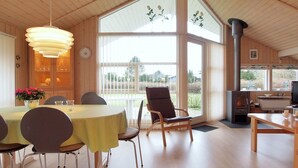 A spacious dining area with a round table and chairs, large windows, a fireplace, and a view of the outdoors. - "Lilia" - 900m from the sea by Interhome (Væggerløse)