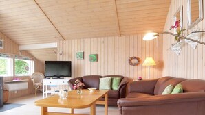 A cozy living room with a wooden ceiling, a television, a sofa, a coffee table, and a lamp. - "Lilia" - 900m from the sea by Interhome (Væggerløse)
