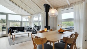Een ruime zithoek met een houten tafel en stoelen, een bank en een open haard.