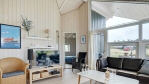 Een ruime woonkamer met een televisie, bank en salontafel.
