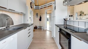 Een moderne keuken met witte kasten, roestvrijstalen apparatuur en een houten vloer.