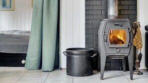 A room with a modern fireplace, a bed, and a window with curtains. - "Aimi" - 270m from the sea by Interhome (Væggerløse)