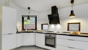 A modern kitchen with white cabinetry, a black range hood, and pendant lighting. - "Aimi" - 270m from the sea by Interhome (Væggerløse)