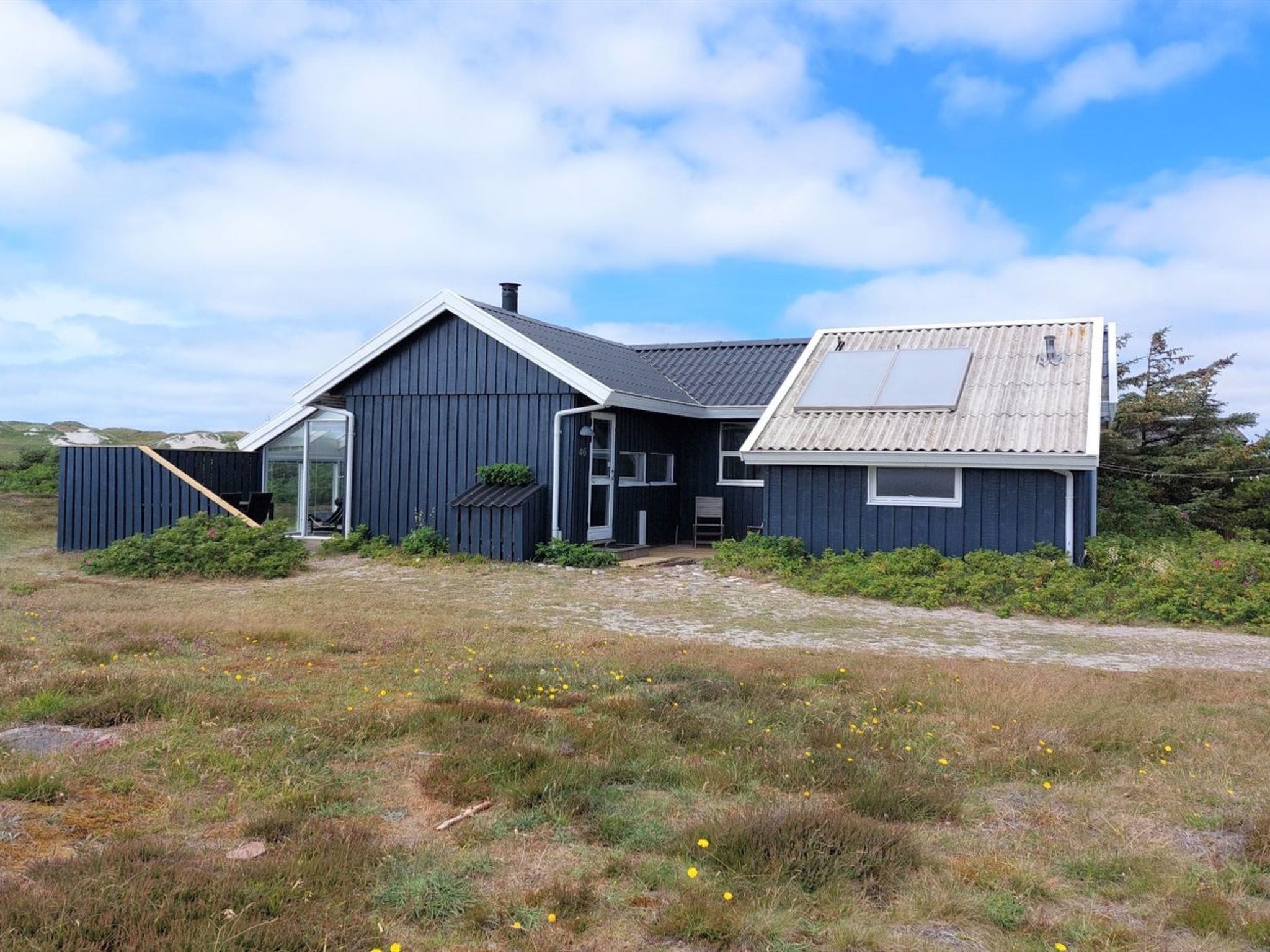 Ein modernes Haus mit großer Garage, überdachter Veranda und einem geneigten Dach mit Solaranlage.