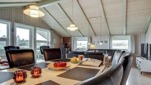 Un vaste espace de vie doté d’un haut plafond, une table à manger dressée pour le repas et un coin salon confortable.