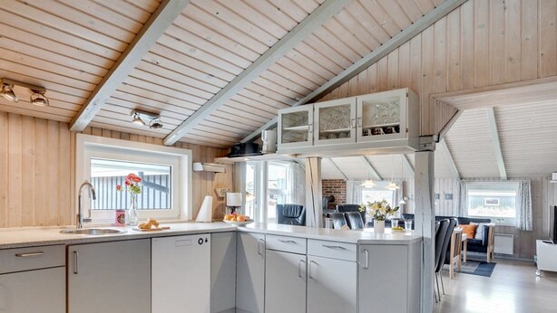 Une cuisine moderne avec des meubles blancs, un four encastré et une fenêtre donnant sur le jardin.