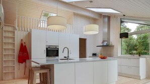 Een moderne keuken met een centraal eiland, witte kasten en een groot raam met uitzicht op groen.