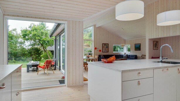 Een moderne keuken met een groot eiland, houten vloeren en hanglampen.