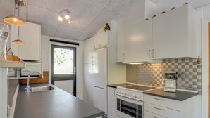 A modern kitchen with white cabinets, a granite countertop, a built-in oven, and a coffee maker.