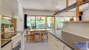 A modern kitchen with a dining area, large windows, and a view of the outdoors.