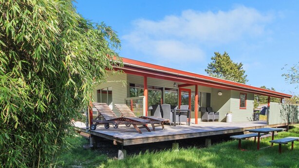 A house with a covered patio area, outdoor seating, and a grassy yard.