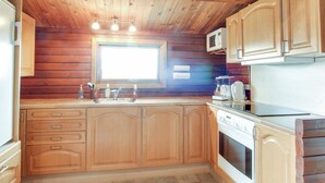 A kitchen with wooden cabinets, a microwave, a stove, and a window. - "Svenne" - 500m from the sea by Interhome (Ringkøbing)