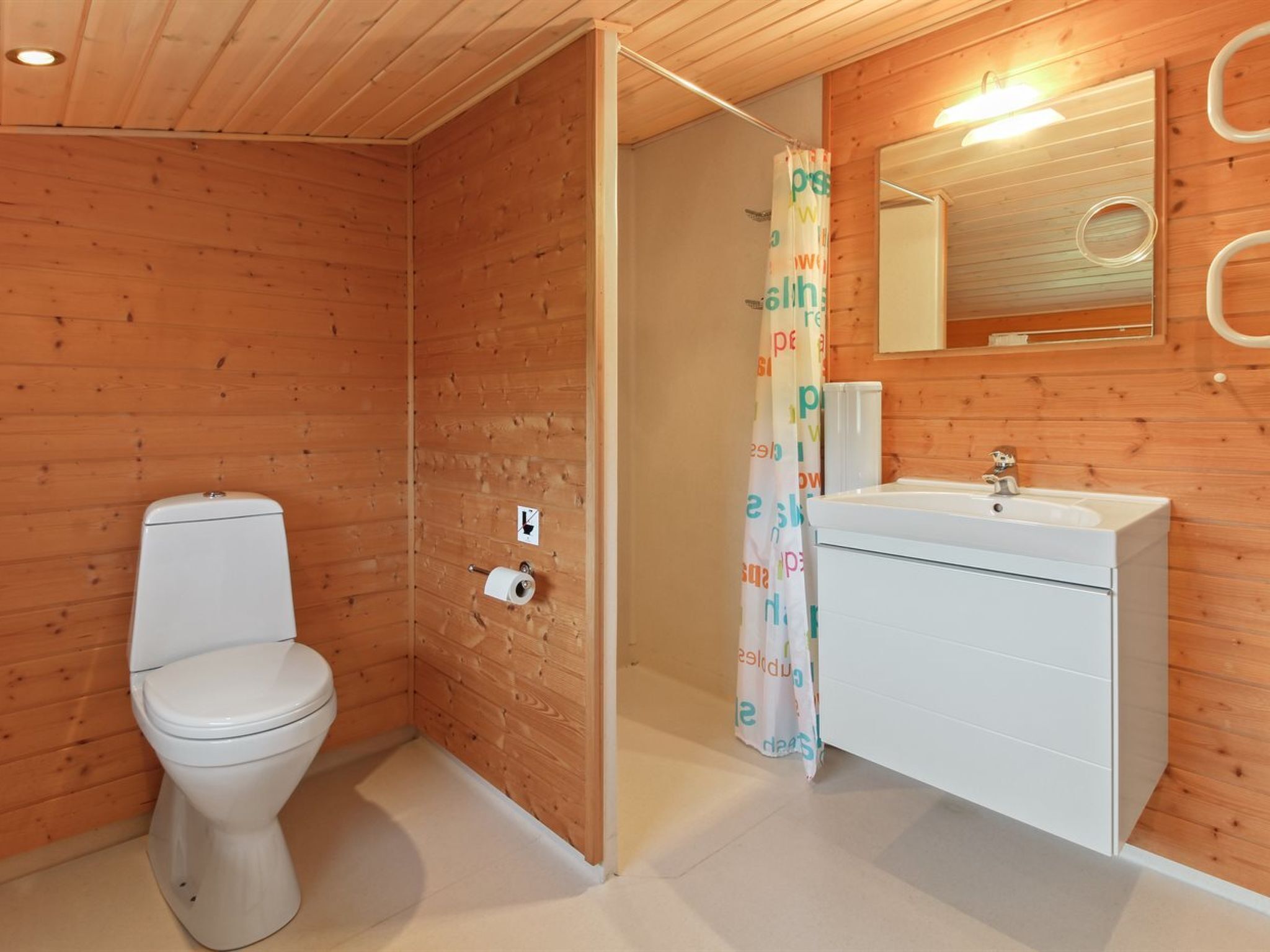 Un baño con paneles de madera, que incluye un inodoro, ducha y lavamanos.
