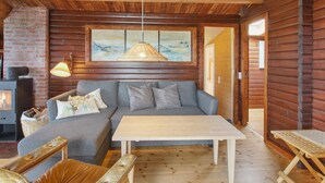 A cozy cabin interior with a sofa, table, and a fireplace. - "Svenne" - 500m from the sea by Interhome (Ringkøbing)