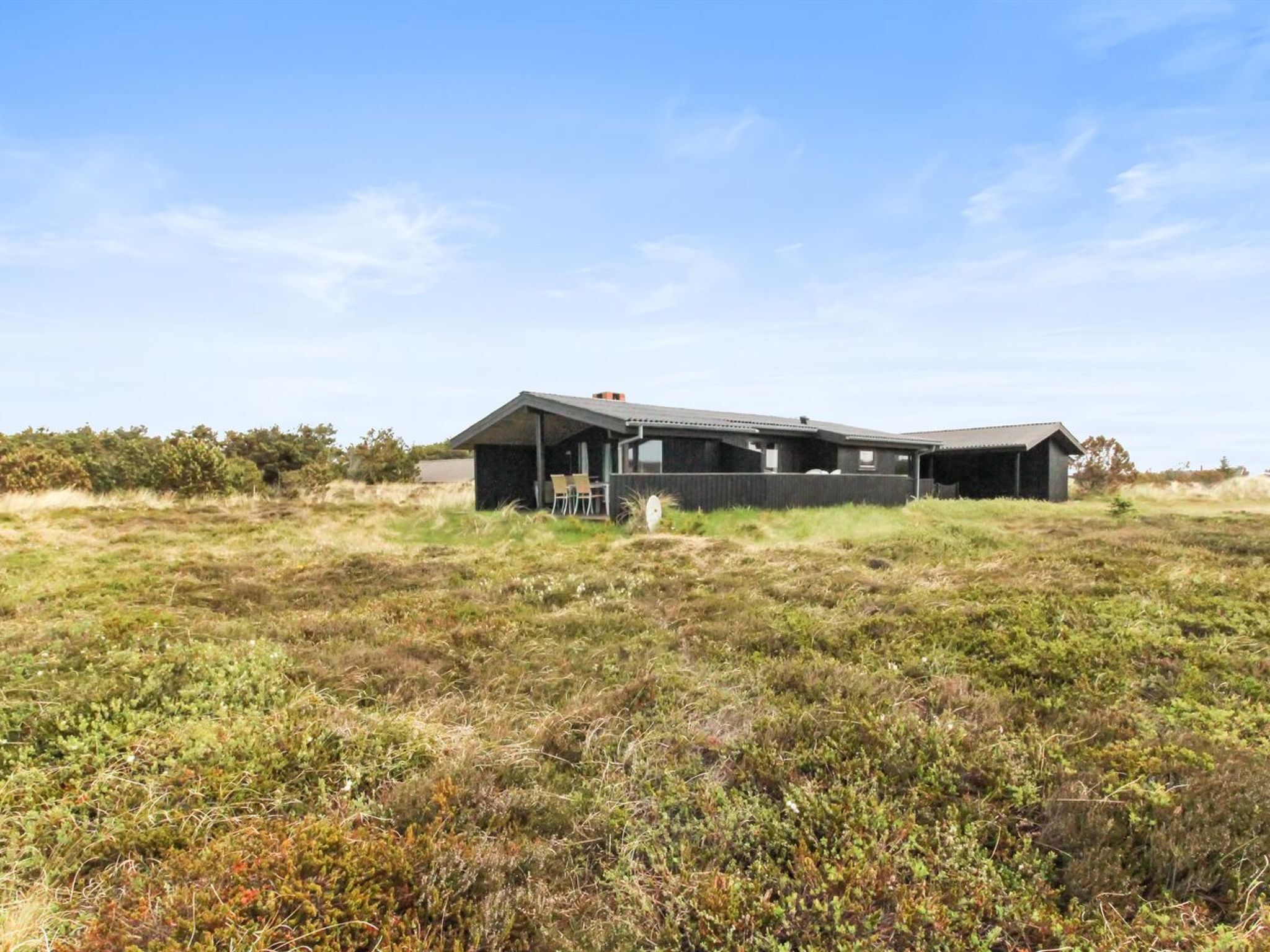A modern house with a large open porch and a covered outdoor seating area.