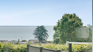Une vue d’une zone côtière avec un grand arbre et un bâtiment en arrière-plan.