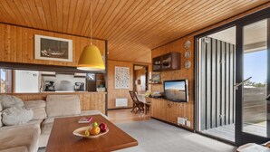 A cozy living room with a wooden ceiling, a dining area with a table set for two, and a kitchen area with a large window. - "Sulo" - 1.4km from the sea by Interhome (Thisted)