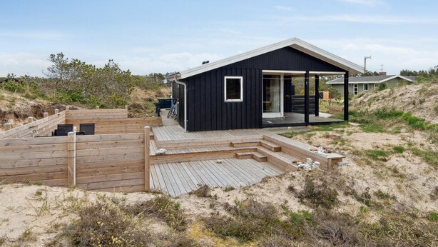 A modern beach house with a wooden deck, a covered outdoor area, and a sandy landscape. - "Sulo" - 1.4km from the sea by Interhome (Thisted)