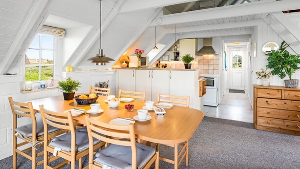 Une cuisine spacieuse avec un plafond haut et un coin repas comprenant une table et des chaises en bois.
